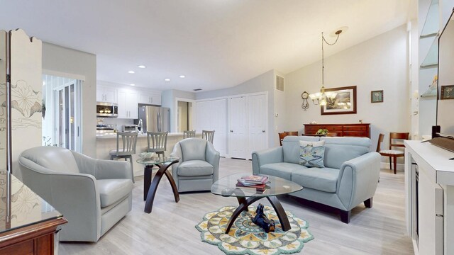 living room featuring visible vents, light wood finished floors, built in shelves, and a notable chandelier