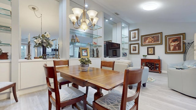dining room with visible vents, an inviting chandelier, light wood-style flooring, and lofted ceiling
