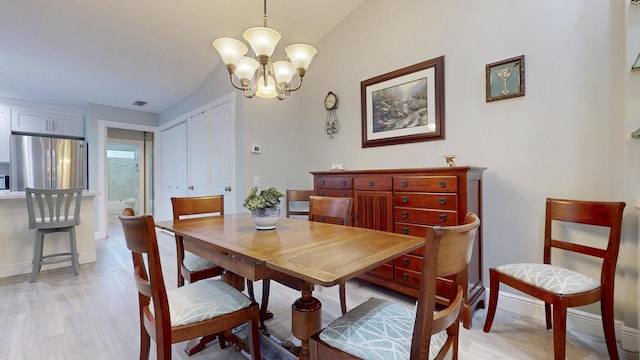 dining room with baseboards, lofted ceiling, light wood finished floors, and a notable chandelier
