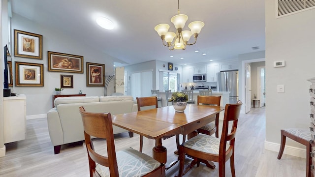 dining area featuring baseboards, visible vents, an inviting chandelier, and light wood-style floors