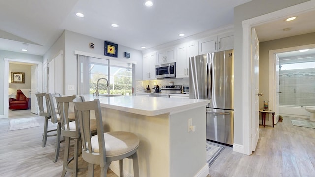 kitchen with a breakfast bar area, stainless steel appliances, a sink, and light wood-type flooring