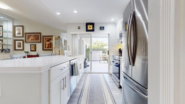 kitchen with a sink, appliances with stainless steel finishes, a center island with sink, and white cabinetry