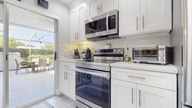 kitchen with stainless steel dishwasher, a sink, light countertops, open floor plan, and white cabinetry