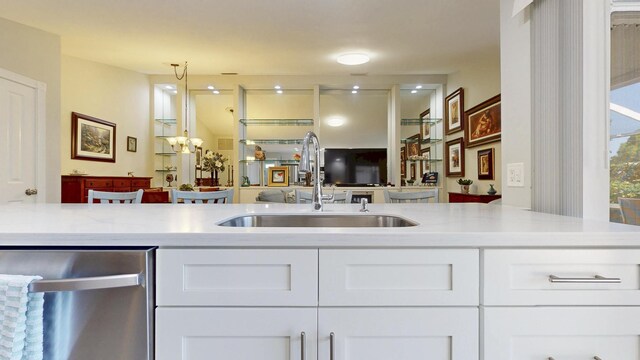 kitchen featuring white cabinets, a sink, light wood-style flooring, stainless steel dishwasher, and visible vents