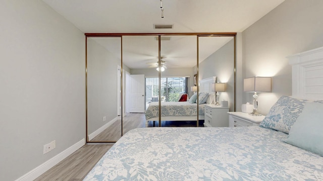 bedroom featuring visible vents, a closet, wood finished floors, baseboards, and ceiling fan