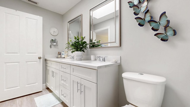 full bath featuring a sink, double vanity, wood finished floors, and visible vents