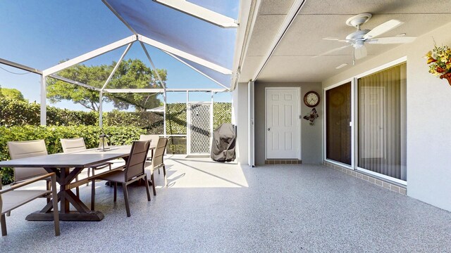 view of patio / terrace with a ceiling fan, outdoor dining space, and glass enclosure