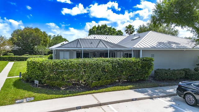 back of house with a lawn, a lanai, and metal roof