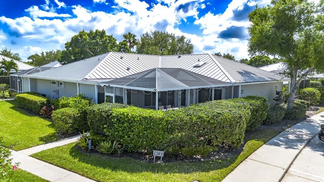 back of property with a yard, a standing seam roof, and metal roof
