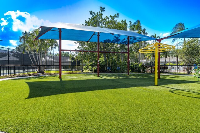 community play area featuring a yard and fence