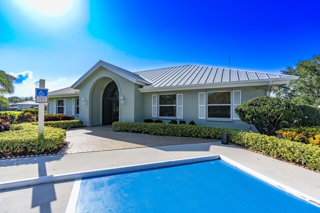 exterior space featuring a standing seam roof, metal roof, an outdoor pool, and stucco siding