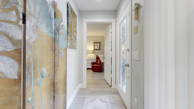hallway featuring baseboards and light wood finished floors