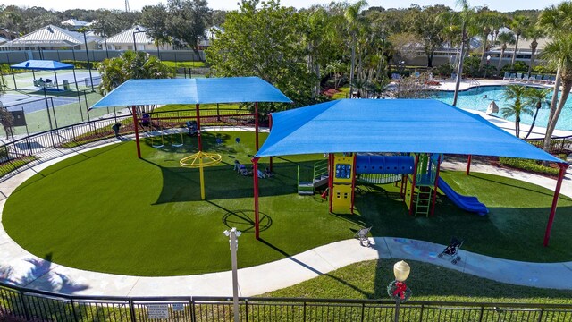 community playground with fence, a community pool, and a lawn