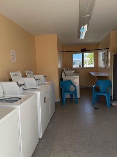103 Oxford 500 Unit 103, West Palm Beach, FL 33417 - community laundry featuring washer and clothes dryer and light tile patterned floors