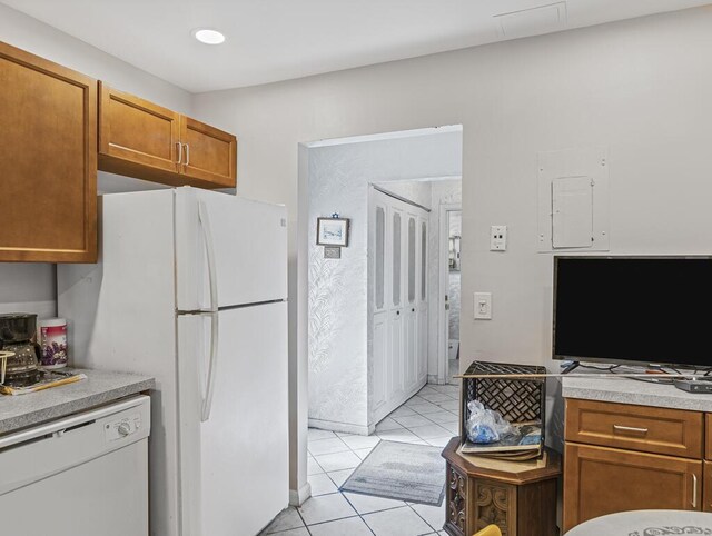 103 Oxford 500 Unit 103, West Palm Beach, FL 33417 - kitchen featuring white appliances, light tile patterned floors, brown cabinetry, and light countertops