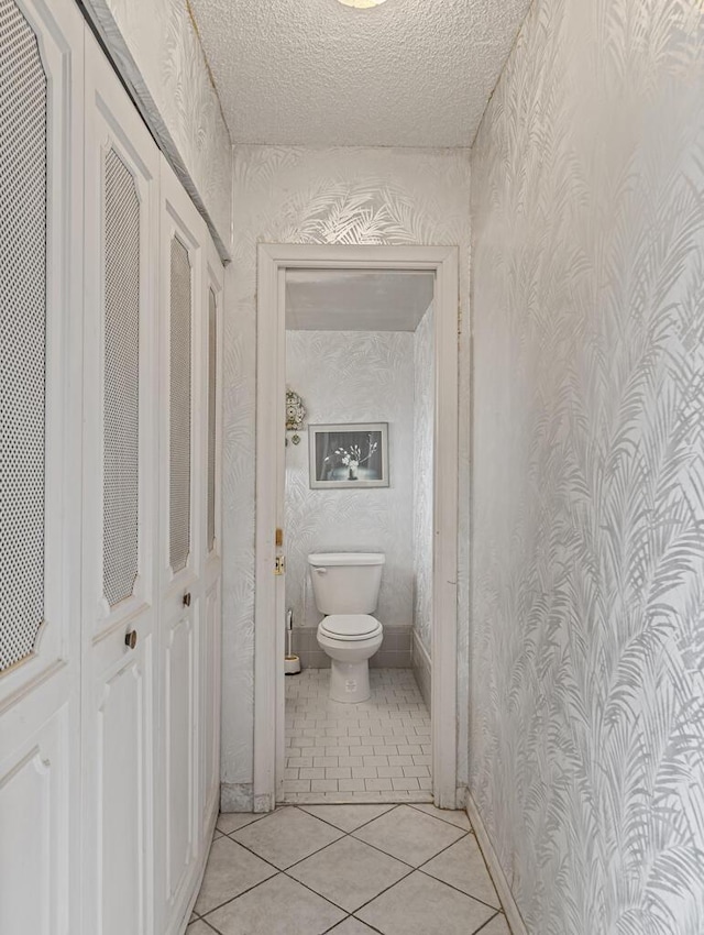 103 Oxford 500 Unit 103, West Palm Beach, FL 33417 - bathroom with wallpapered walls, toilet, tile patterned flooring, and a textured ceiling