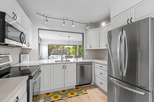 kitchen with a sink, appliances with stainless steel finishes, light wood finished floors, and white cabinetry