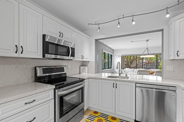 kitchen featuring decorative backsplash, light stone countertops, white cabinets, a sink, and appliances with stainless steel finishes
