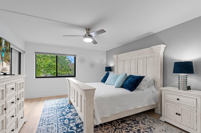 bedroom featuring light wood-type flooring, baseboards, and ceiling fan