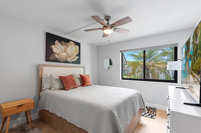 bedroom with baseboards, ceiling fan, and light wood-type flooring