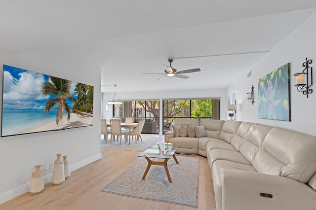 living room featuring baseboards, a ceiling fan, wood finished floors, and visible vents