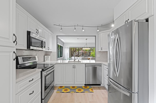 kitchen with light wood-type flooring, white cabinetry, light stone counters, a sink, and appliances with stainless steel finishes