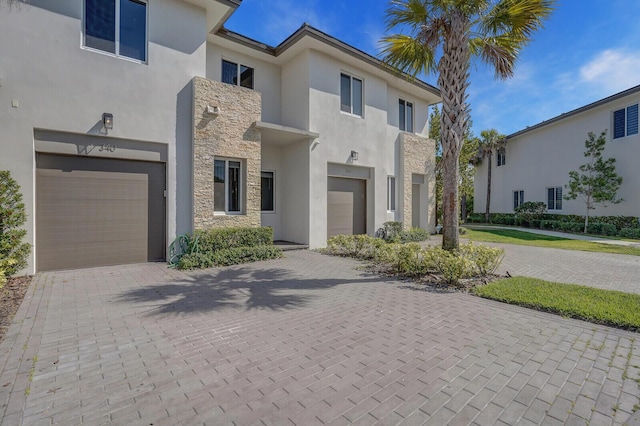340 Pioneer Way, Royal Palm Beach, FL 33411 - view of front of house featuring a garage, stucco siding, decorative driveway, and stone siding