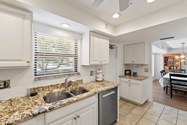 kitchen featuring a sink, light tile patterned flooring, white cabinets, stainless steel dishwasher, and light stone countertops