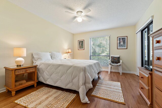 bedroom featuring light wood-type flooring, baseboards, a textured ceiling, and ceiling fan