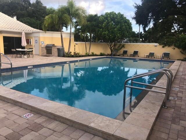 community pool featuring exterior kitchen, a patio, fence, and a grill