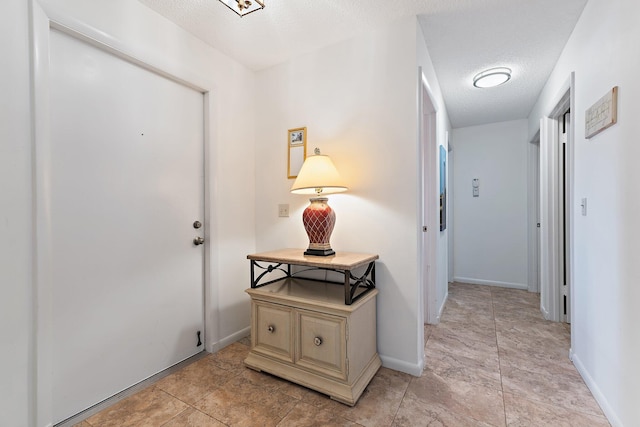 foyer with a textured ceiling and baseboards