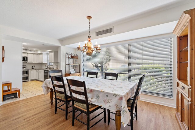 dining space featuring a chandelier, light wood finished floors, plenty of natural light, and baseboards