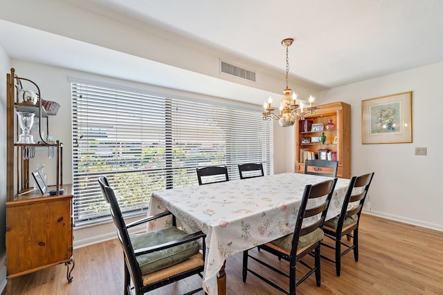 dining room with a chandelier, plenty of natural light, light wood-type flooring, and baseboards