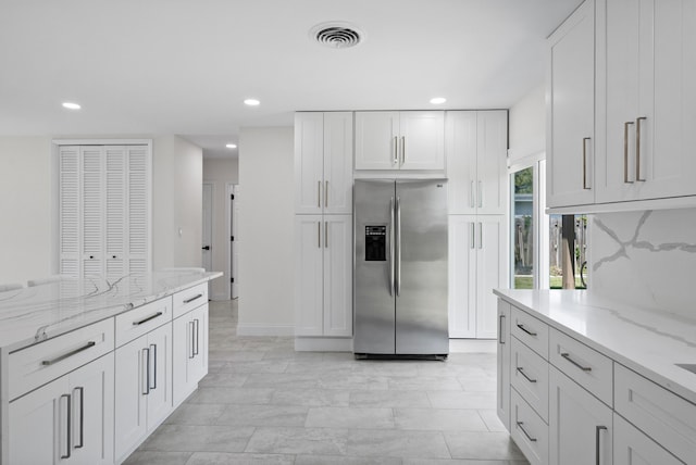 1625 Seaway Dr, Hutchinson Island, FL 34949 - kitchen with stainless steel fridge with ice dispenser, recessed lighting, white cabinetry, light stone countertops, and baseboards