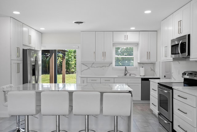 1625 Seaway Dr, Hutchinson Island, FL 34949 - kitchen with stainless steel appliances, a sink, a kitchen bar, recessed lighting, and tasteful backsplash