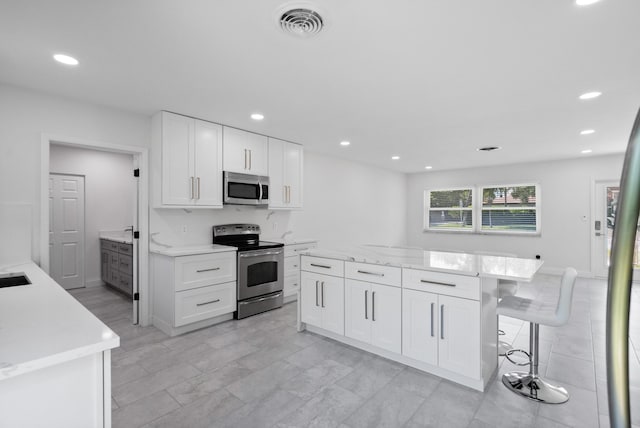1625 Seaway Dr, Hutchinson Island, FL 34949 - kitchen featuring stainless steel appliances, white cabinetry, recessed lighting, a kitchen island, and a kitchen breakfast bar