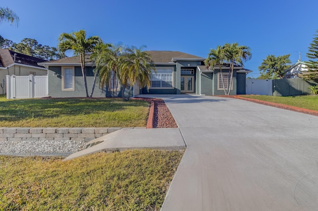 ranch-style house featuring driveway, french doors, a front yard, a gate, and fence