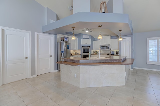 kitchen featuring stainless steel appliances, ceiling fan, light tile patterned floors, and high vaulted ceiling