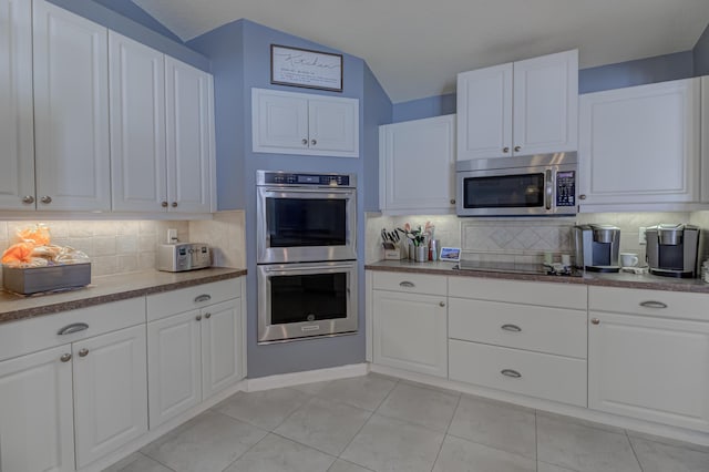kitchen featuring decorative backsplash, lofted ceiling, white cabinets, and stainless steel appliances