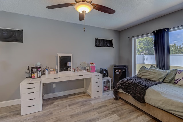 bedroom with light wood-style floors, a textured ceiling, ceiling fan, and baseboards