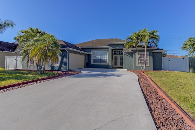 view of front of home with driveway, french doors, a garage, a front lawn, and stucco siding