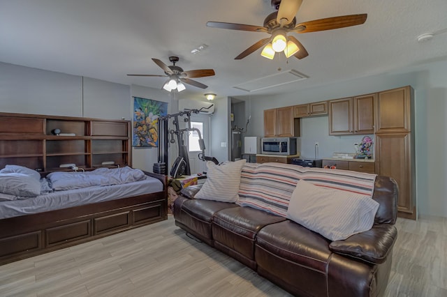 bedroom with attic access, light wood-style flooring, and ceiling fan