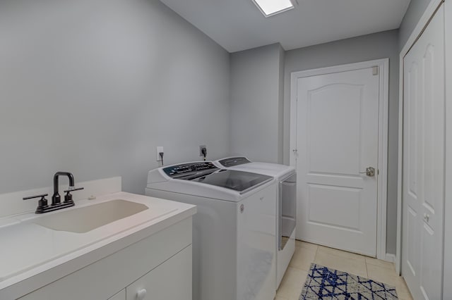 laundry room with a sink, light tile patterned floors, cabinet space, and independent washer and dryer