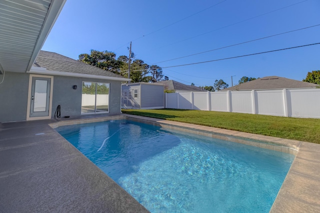 view of swimming pool with fence, a yard, a fenced in pool, an outbuilding, and a storage shed