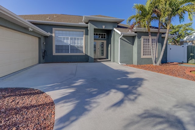 single story home with an attached garage, stucco siding, french doors, and concrete driveway