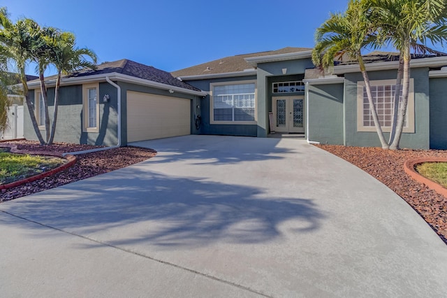 view of front facade featuring french doors, stucco siding, driveway, and a garage