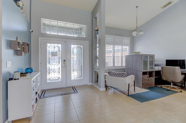 foyer entrance featuring french doors, visible vents, tile patterned floors, a chandelier, and a high ceiling