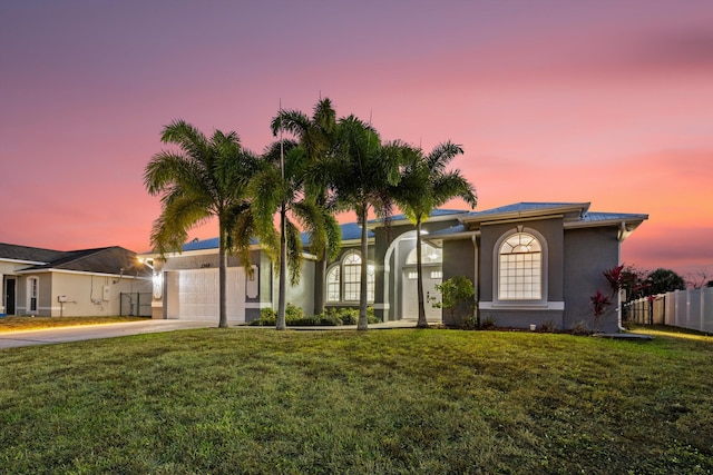 view of front facade with a front lawn, fence, stucco siding, concrete driveway, and an attached garage