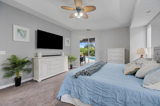 carpeted bedroom with access to outside, a raised ceiling, baseboards, and multiple windows