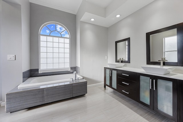 full bath featuring baseboards, a sink, a garden tub, and double vanity